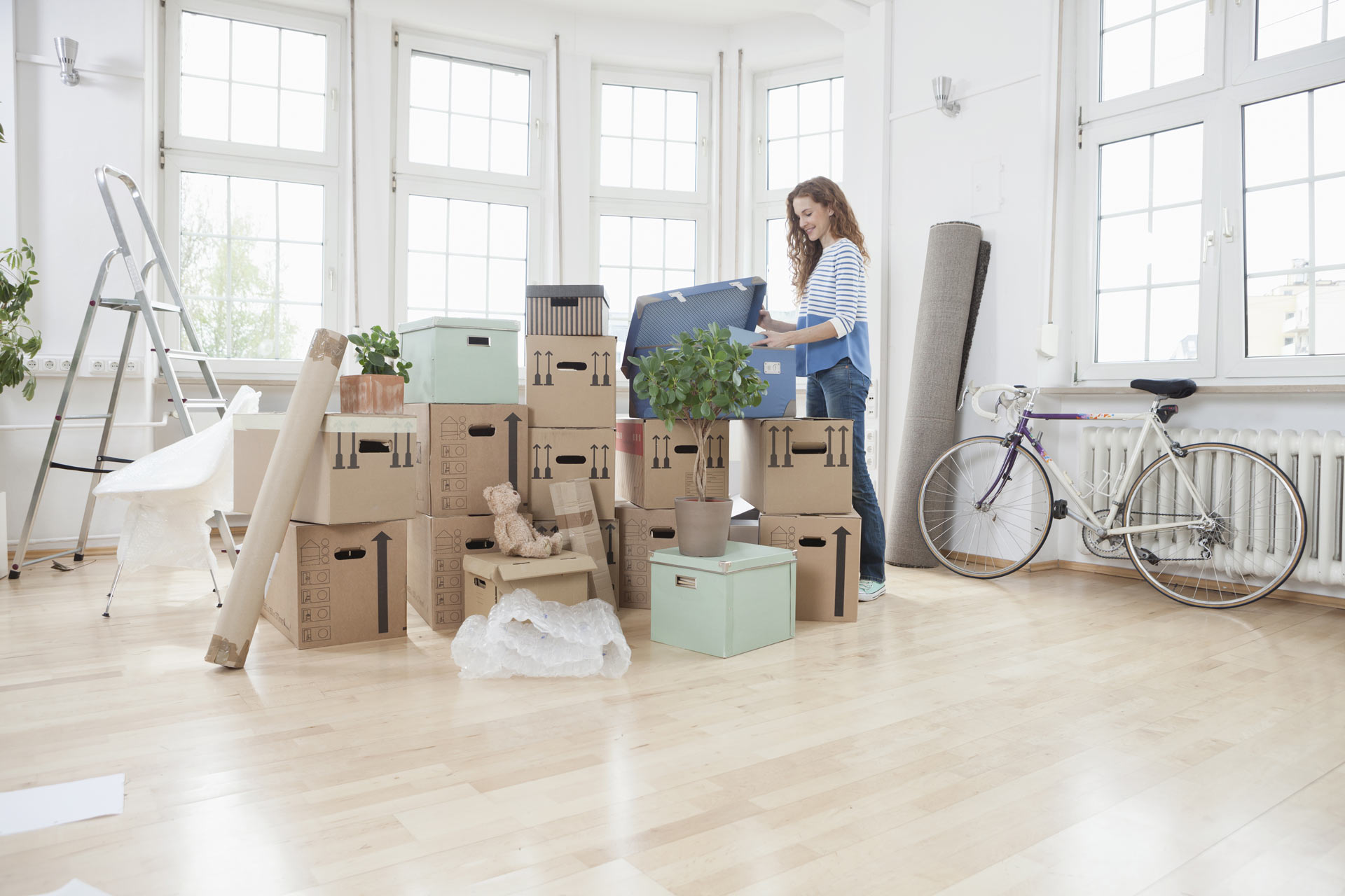 Femme arrangeant des cartons dans une pièce avec de grandes fenêtres